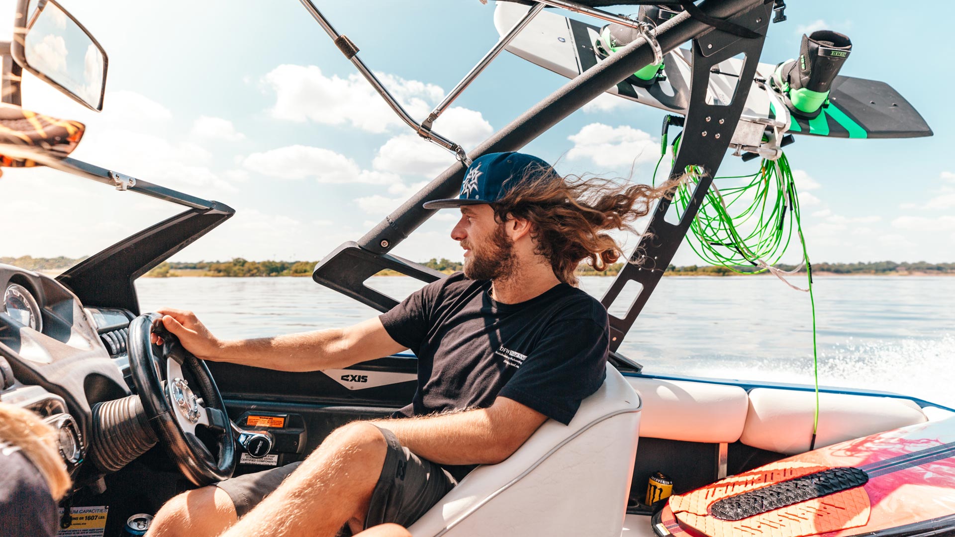 Pilote de bateau tractant un wakeboard sur un plan d'eau, avec vue sur l'équipement nautique et le ciel dégagé
