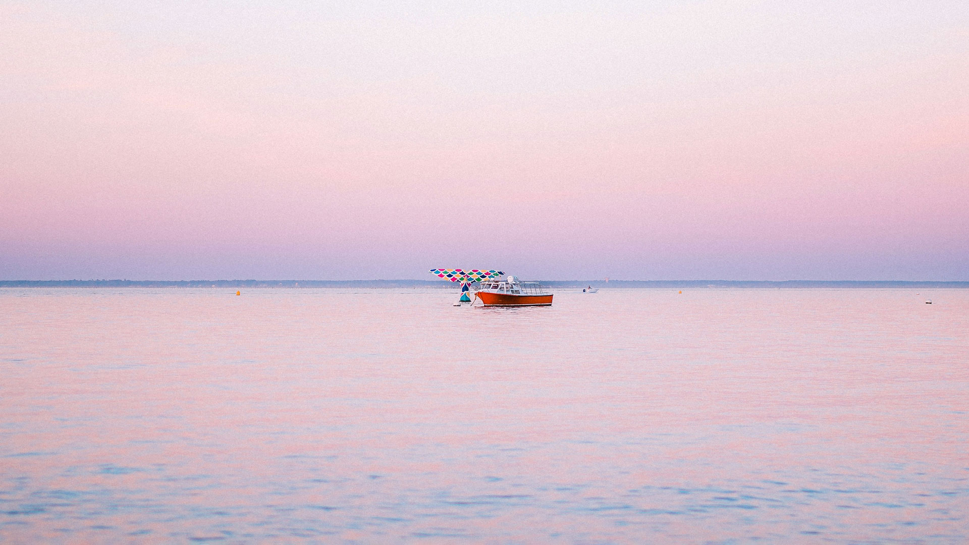 Queue de la baleine Arcachon au coucher du soleil avec bateau devant l’œuvre emblématique sur le Bassin d’Arcachon