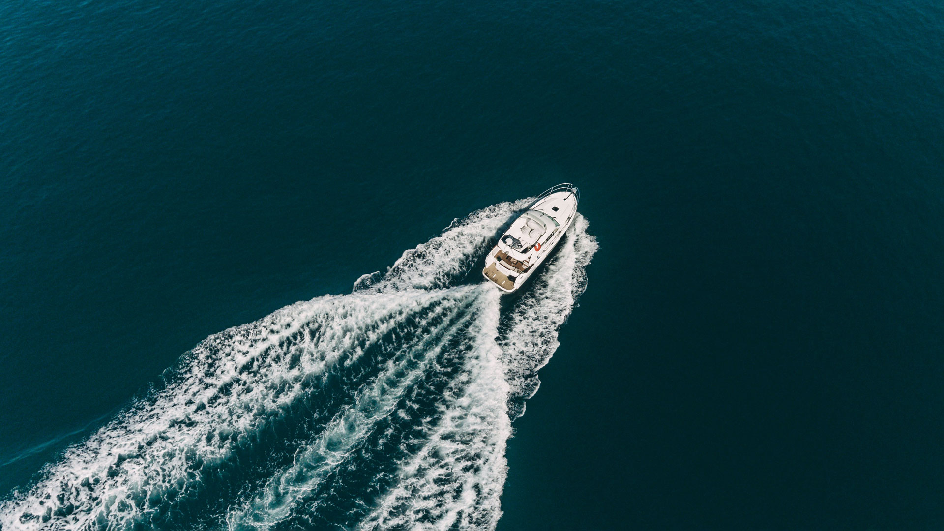 Vue aérienne d’un bateau à moteur naviguant en mer, laissant une traînée d’écume derrière lui