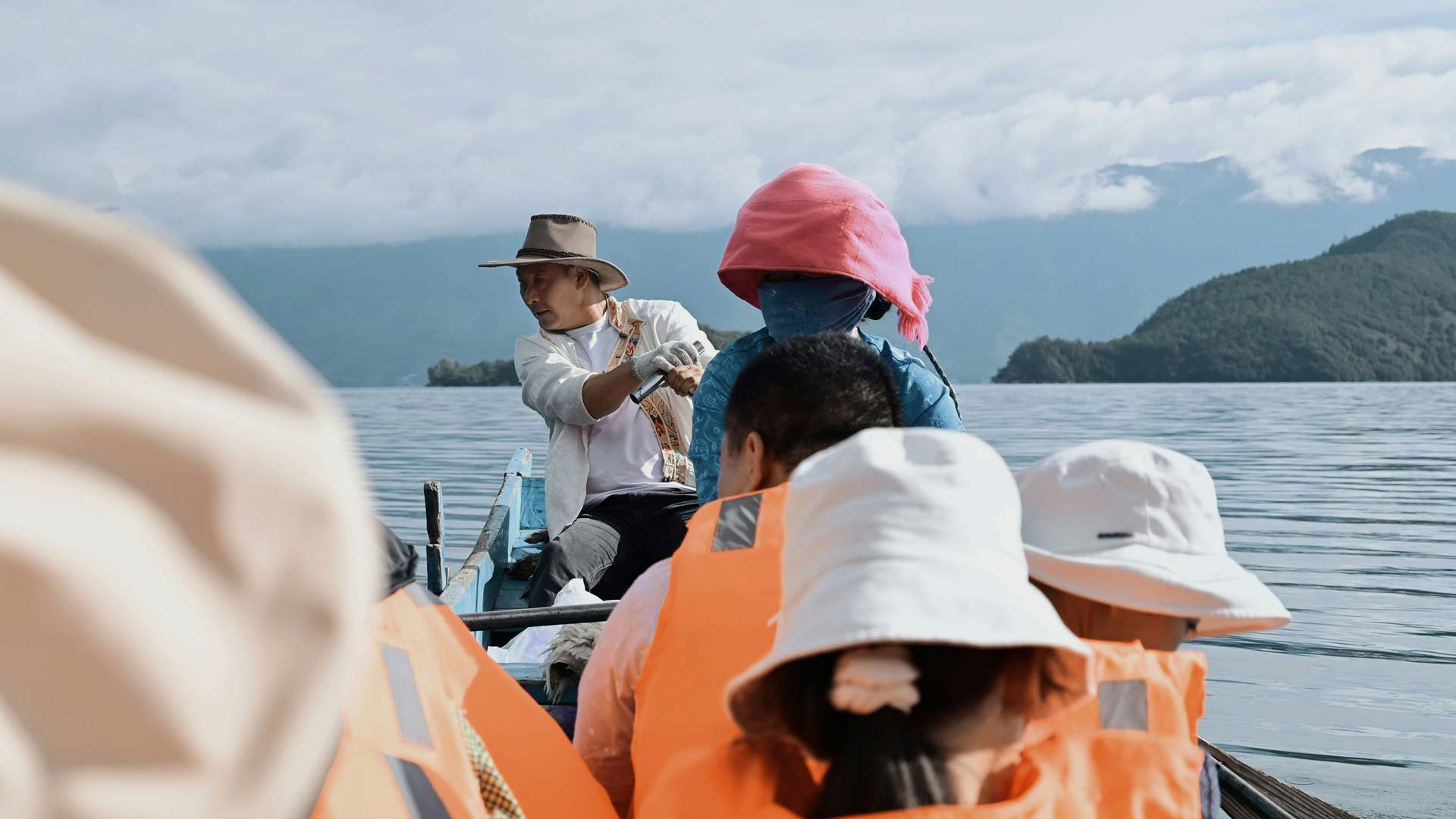 Sortie en bateau avec des enfants portant des gilets de sauvetage sur un lac entouré de montagnes