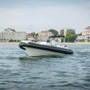 Vue latérale du semi-rigide Nuova Jolly NJ 850 XL amarré au port, montrant son design élégant et son bain de soleil avant.